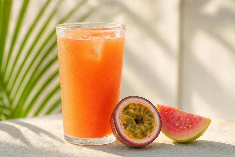 Tall glass of orange POG passion-orange-guava juice with a halved passion fruit and guava wedge