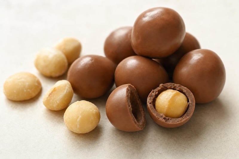 Milk-chocolate-covered Hawaiian macadamia nuts, one broken open to show the nut inside