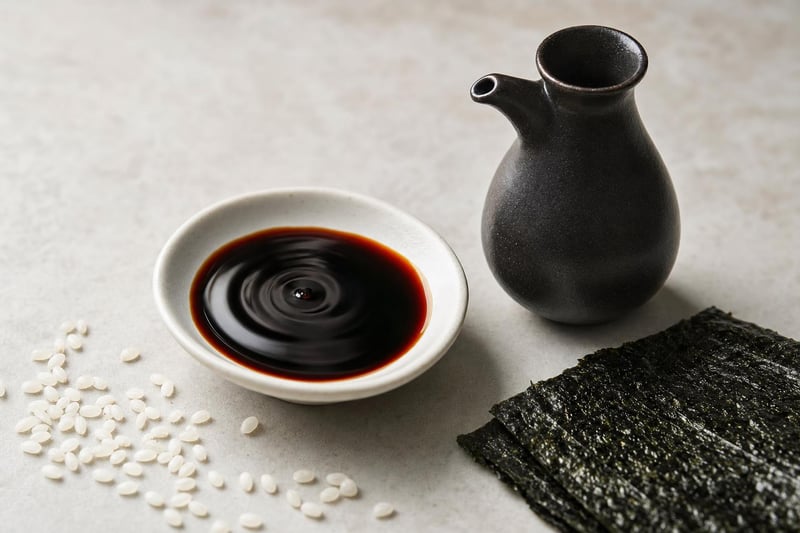 Dish of dark Hawaiian shoyu with a ceramic cruet, rice grains, and nori