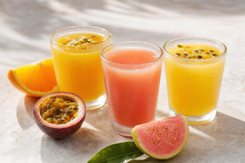 Three glasses of Hawaiian tropical juice — passion-orange-guava, guava, and lilikoi — with fresh fruit